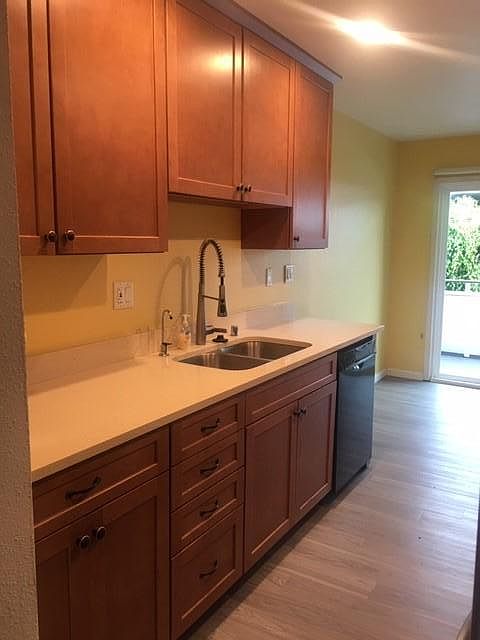 Kitchen with new cabinets and new appliances (view from entrance hallway). New laminate wood-like floor.
