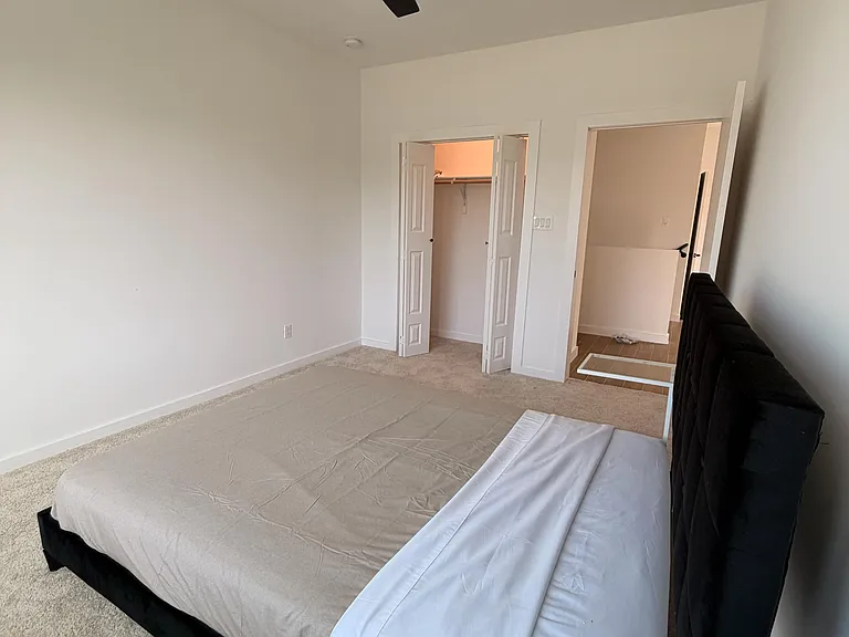 Spacious carpeted bedroom with a ceiling fan, room for a full/queen bed, and a walk-in closet for ample storage.