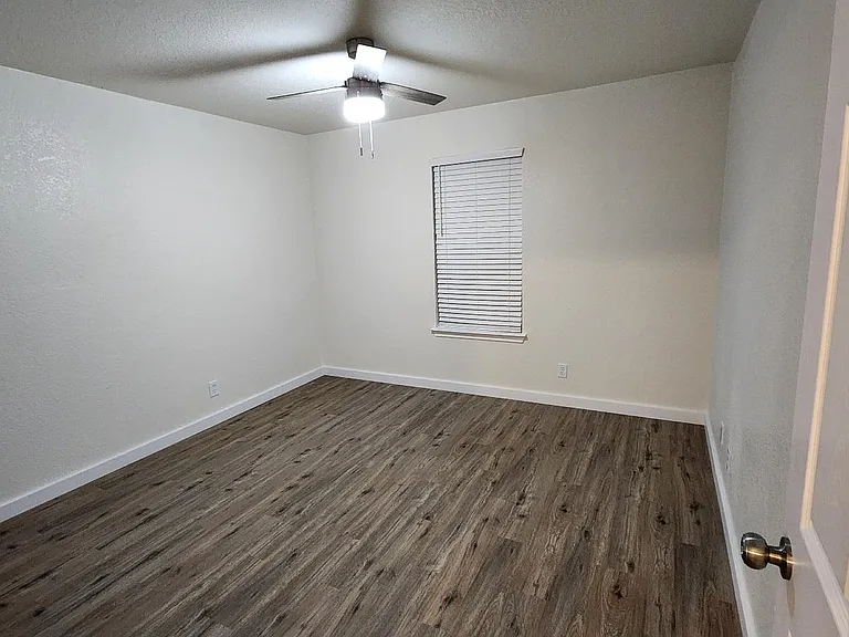 Large front bedroom (12' x 12') with 2" faux wood blinds and modern ceiling fan.