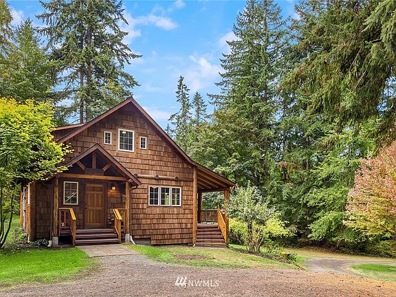 The home is shingled with log accents and covered entry decks all around. This north-facing entry is adjacent to a generous, level parking area.