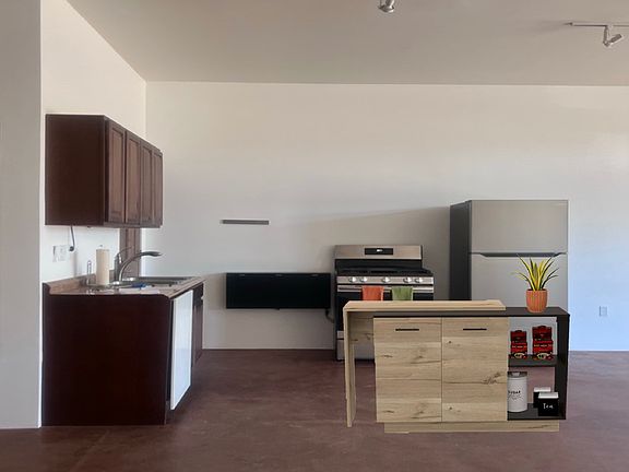 Kitchen includes this island, double stainless steel sink, dishwasher, black prep shelf, knife wall-magnet, stove, fridge.