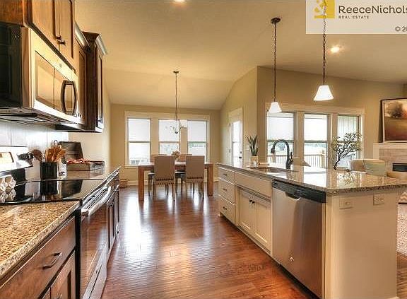 Stainless steel appliances, large island, beautiful hardwood floors in kitchen and dining areal