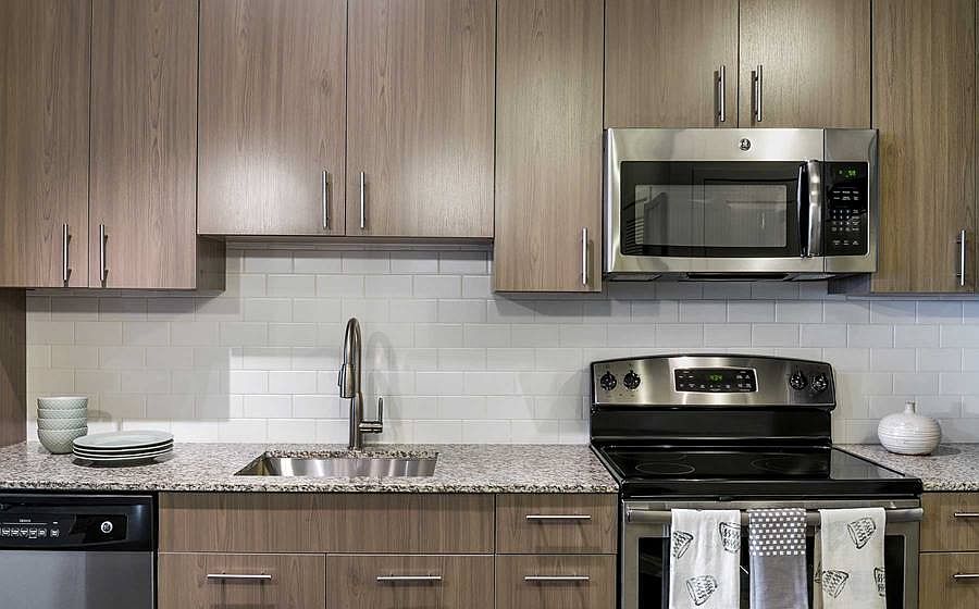 Kitchen with brown cabinetry, granite countertops with tile backsplash and stainless steel appliances