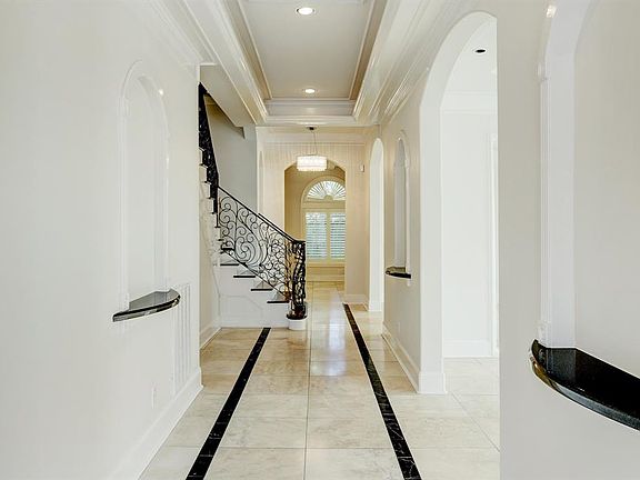 Beautiful entry with Travertine floors throughout and ornate staircase banister.