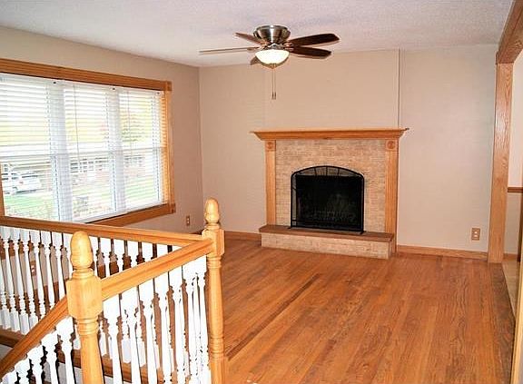 Open and beautiful living room with real wood floors, beautiful brick fireplace with wood mantel and hearth, newer lighting, new windows, new banister