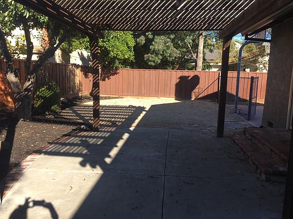 Backyard with patio, awning, and concrete sideboard with basketball hoop
