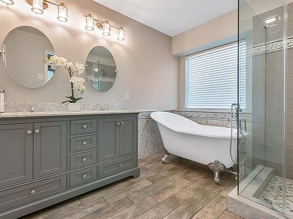 Completed in August 2019, this stunning Master Bath has been remodeled and features wood-look tile floors, claw foot soaking tub, frameless glass shower and Carrara marble vanity, basket weave tub surround and shower accents.