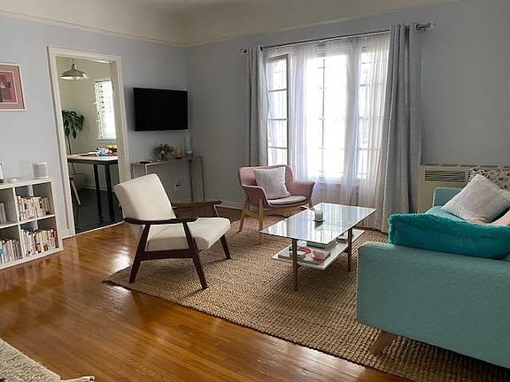 Living room seen from entry, original hardwood floors. Dining area in kitchen seen through doorway.