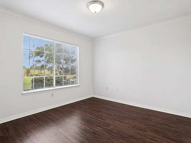 Bright, unfurnished room with elegant dark hardwood floors and large window with scenic outdoor view.
