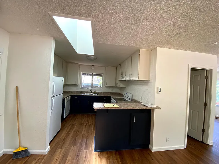 Kitchen from the dining area, also showing the door to the upstairs laundry room and the upstairs 1/2 bath