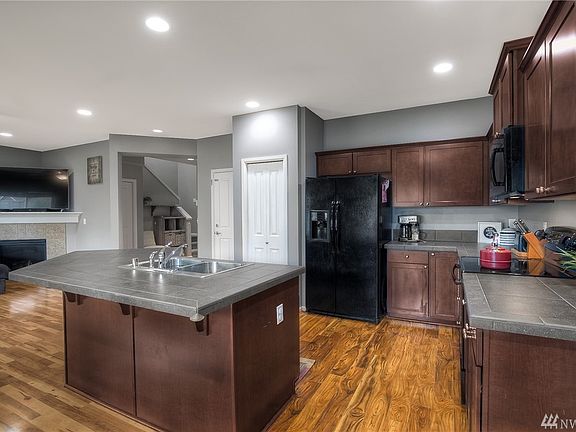 The attractive user-friendly kitchen boasts black & stainless appliances, oversized breakfast bar island & dark tile counters. 