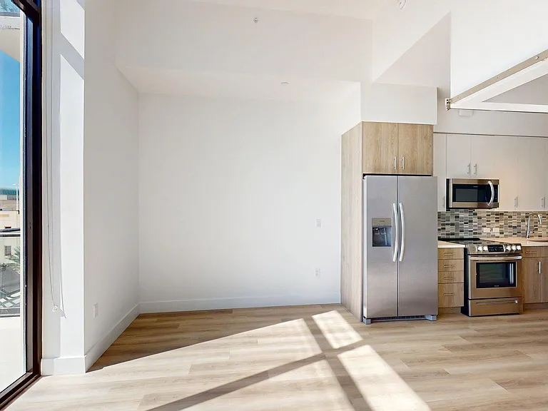 Apartment Kitchen with Stainless Steel Appliances, Dining and Living Room with Wood Style Flooring and Patio/Balcony.