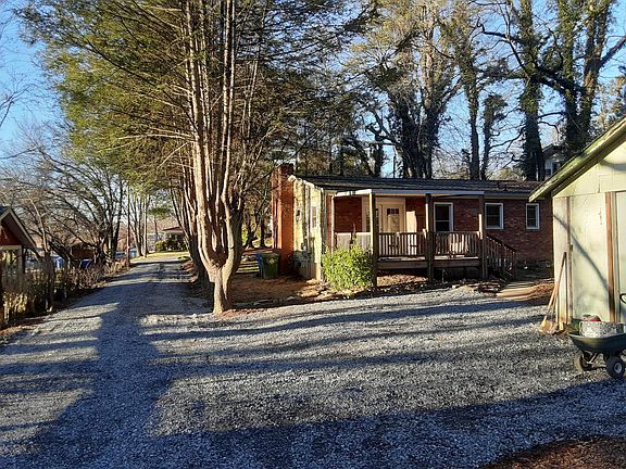 View of parking spaces, driveway, back of house, side of shed