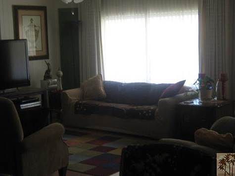Large living space with two large windows with sun screens. Custom paint with decorator features. Home features wood laminate flooring perfect to show off designer area rugs!