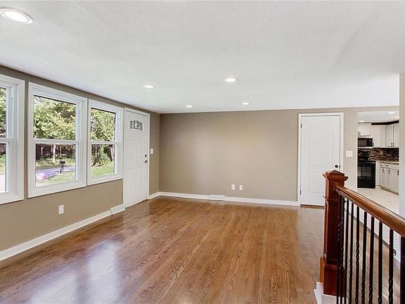 Alternate view of the living room with a peek into the kitchen. Updated railing for a modern feel.