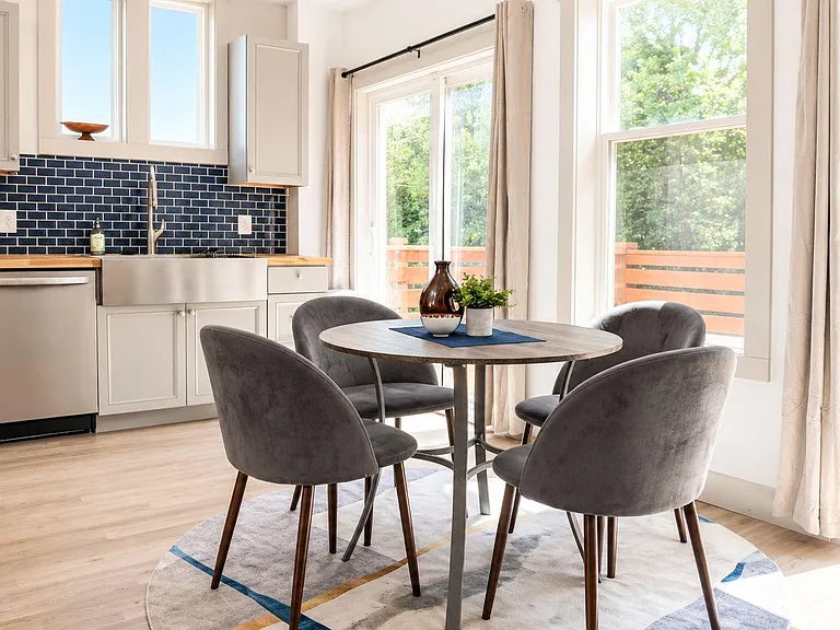 Eat-in kitchen and dining nook with round table seating, ample cabinetry, and large windows/slider opening to a deck.