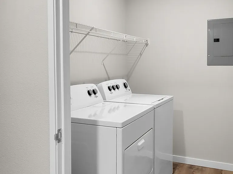 Bright utility room featuring modern washer and dryer with ample shelving space. Bright utility room featuring modern washer and dryer with ample shelving space.