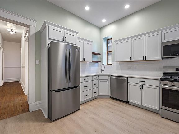 BRAND NEW kitchen that showcases sleek cabinetry, quartz countertops, stainless steel appliances, and ample storage.