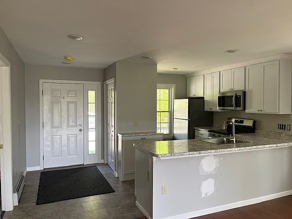 front door leads into space with kitchen on the left