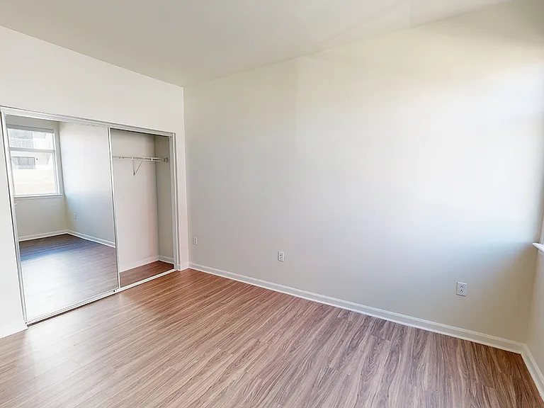 Spacious apartment bedroom with wood-style flooring.