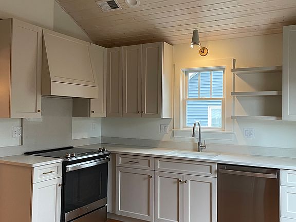 Luxury kitchen with custom handmade cabinets, quartz counters, stainless appliances, vaulted wood ceiling, full glass door to back yard.
