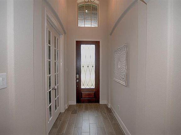 The high ceiling foyer with wood-look tile flooring greets you as you enter the home. A study with French doors is on the left.