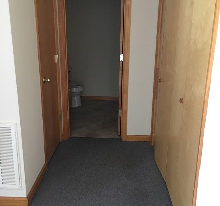 Hallway to bathroom and washer/dryer connections behind bifold doors, linen closet