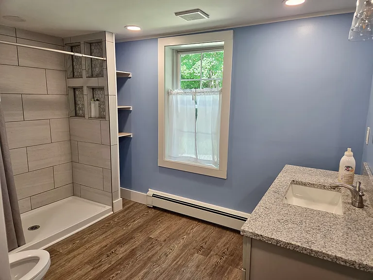 Fully-renovated bathroom with large walk-in shower and plenty of storage for towels and linens.