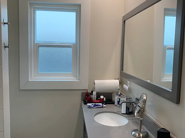 Unit 11 bathroom with shower with matching gray vanity & mirror with gray quartz countertop.