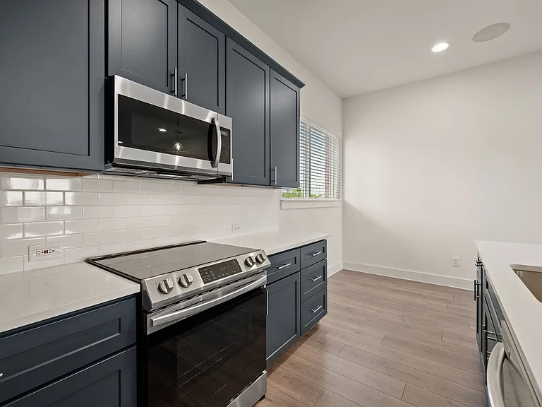 Kitchen view with beautiful island that seats four with elegant pendant lighting. Speakers located in top right are part of a robust system throughout the townhome.