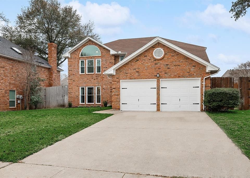 Traditional-style home with brick siding, a garage, driveway, and a shingled roof