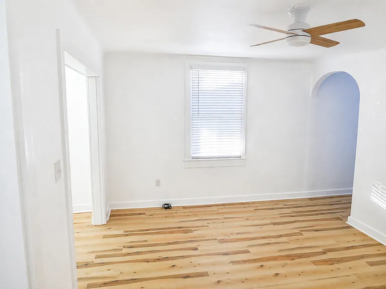 Spacious living area with natural light, open layout, and original architectural arch detail