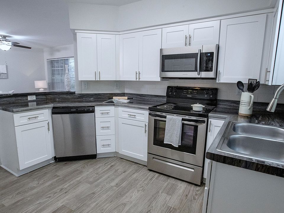 The black fusion countertops, white shaker cabinetry, and stainless-steel appliances add a touch of elegance to your kitchen, surrounded by ample cabinet space for all your culinary essentials.