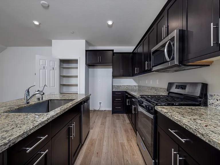 Modern kitchen with granite countertops, dishwasher, and ample cabinet storage. Convenient layout with easy access to the garage, combining functionality and contemporary design. Refrigerator not included.