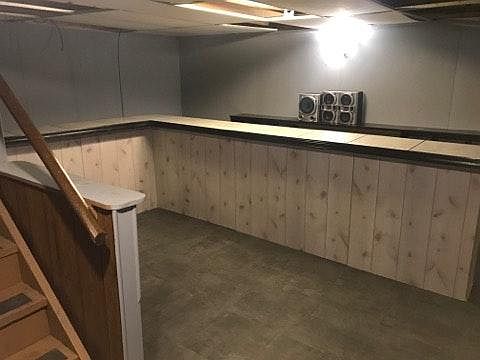 Partially finished walk out basement with large bar.