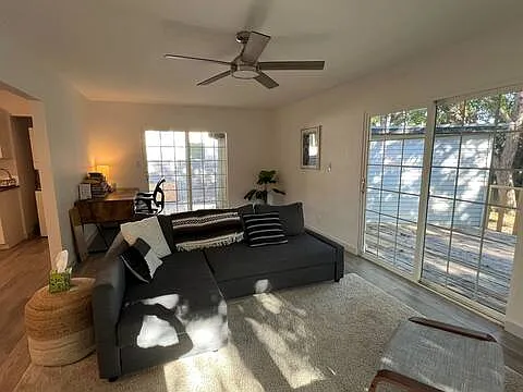 The back living room with sliding doors to the backyard deck. A dedicated workspace and desk is seen behind the couch.