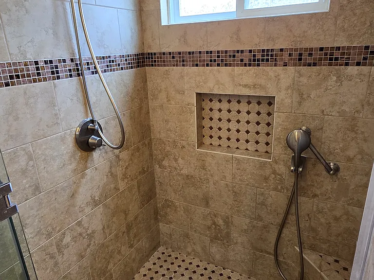 Shower features recessed soap niche and separate shower sprayer arm accessible from shower seat