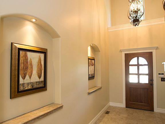 Soaring Foyer welcomes guests with elegant lighted Art Niches, Versailles-pattern tile floors, beautiful alder Entry door and trend-setting pendant light fixture.