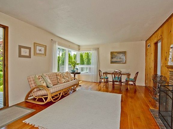 The light filled living room features refinished fir floors, an interior wall fireplace and room for your dining table and chairs.