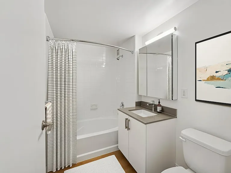 Renovated Package I bath with grey quartz countertop, white cabinetry, and hard-surface flooring