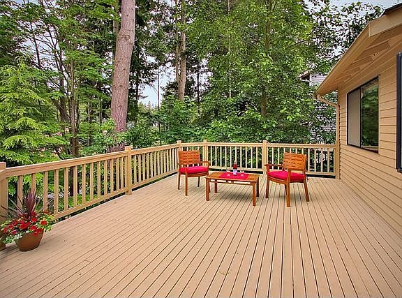 Large back deck surrounded by mature greenery