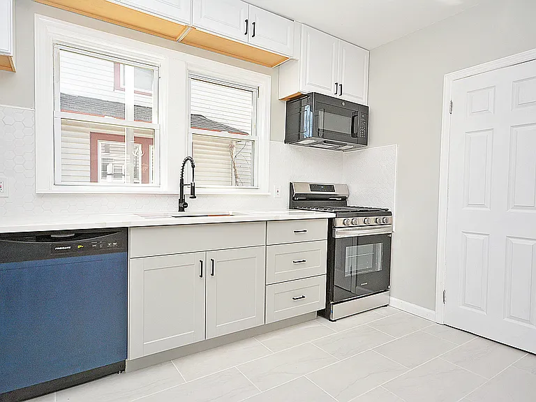 Kitchen - tile backsplash, quartz counters, new appliances, and door to the pantry.