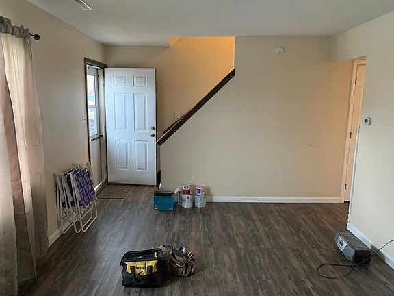 Living room view opposite entry and stairs, hallway, 1/2 bath, and kitchen to right