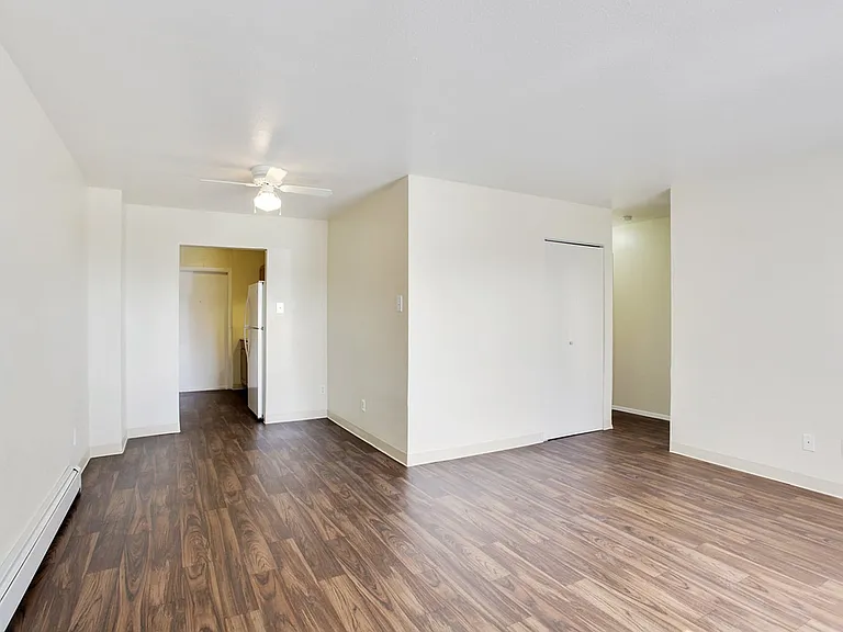 Bright apartment with sleek wooden floors and an inviting open layout leading to a kitchen area.