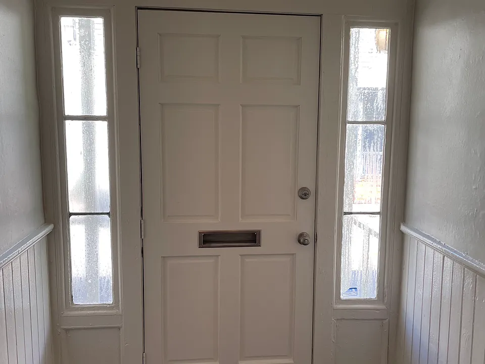 Interior front door freshly painted white trim and wainscoting with grey walls
