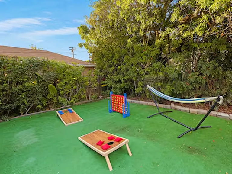 Enjoy the private outdoor space featuring a spacious hot tub that seats 6_8 guests and a cozy fire pit, perfect for relaxing after a beach day. The area also includes a barbecue grill and lawn games, ideal for outdoor dining and fun.