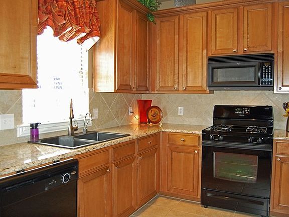 Kitchen has black appliances and abundant cabinets