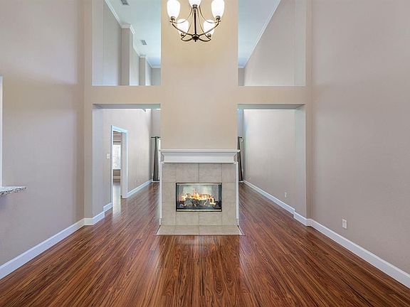 Front view of the living and dining room with soaring ceilings & separated by the gas log fireplace.