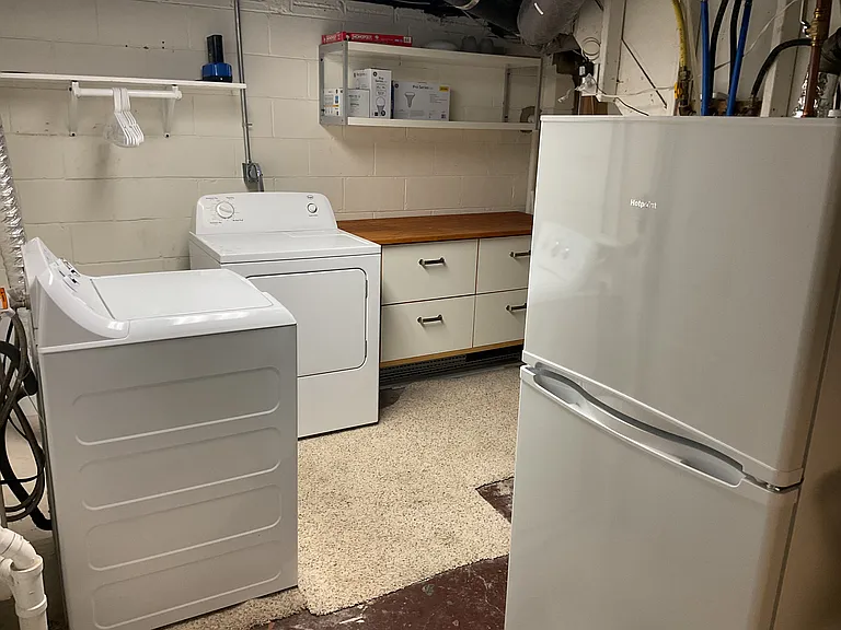 Laundry room comes with washer, dryer, extra refrigerator, water softener, and storage space.