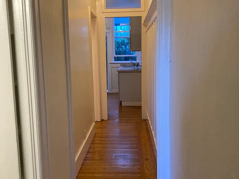 Hallway from living room - bathroom to the left followed by bedroom entrance on the left before kitchen
